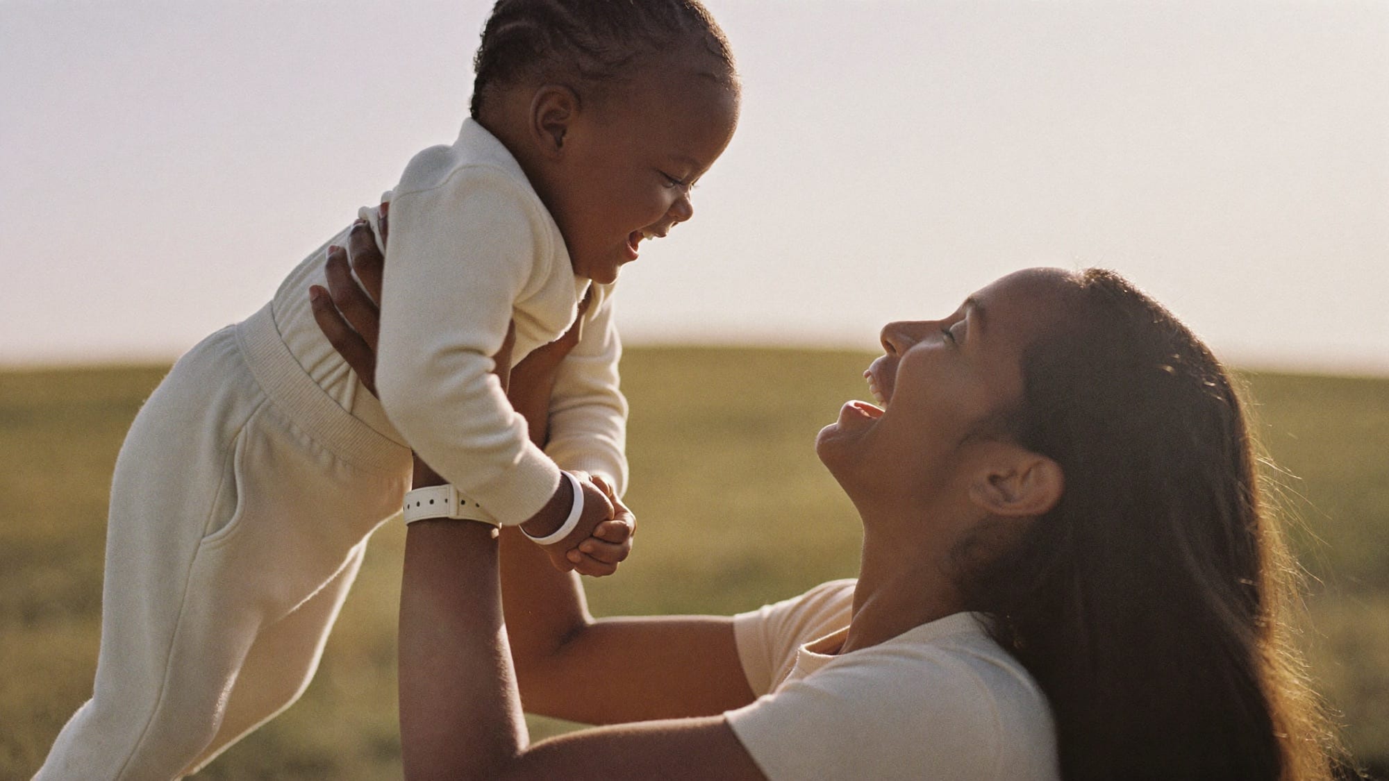 A parent lifting a laughing child into warm golden-hour light